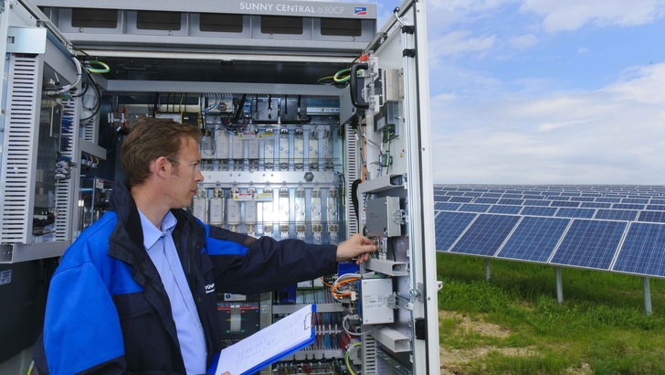Ein Techniker überprüft den Wechselrichter eines Solarparks. - © TÜV Rheinland
