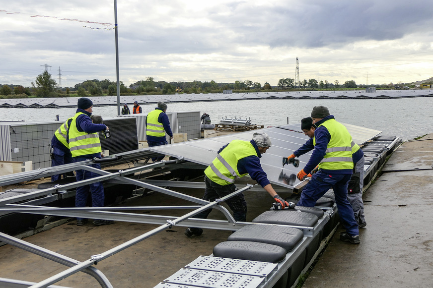 Arbeiter bauen ein Solarschiff auf die Schienenführung. So können sie es leichter ins Wasser schieben.