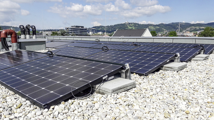 Flach aufgeständerte Photovoltaikmodule auf dem Dach des Mehrfamilienhauses.