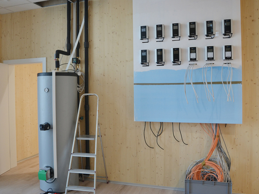 Die Heizzentrale in der Bauphase: Auf der Wand im Eingangsbereich werden die AC-Thor-Geräte sichtbar verschaltet. Der Wärmespeicher (links) mit dem Elwa-Heizstab funktioniert schon.