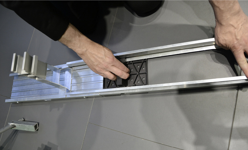 Danach schiebt er die Arretierung in Richtung Modulstütze. So wird das Ende der Verbinderschiene auseinandergedrückt und alles ist fest arretiert.