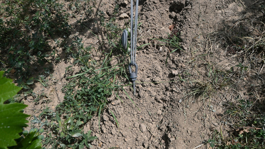 Ein spezieller Anker fixiert die Stahlseile fest im Boden, die die Konstruktion stützen.