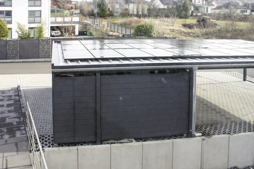 Die flachen Carports schaffen große Solarflächen, verschwinden aber nahezu aus der Optik des Gebäudes.