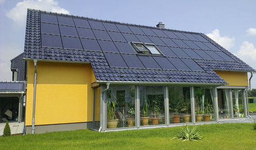 
Über den Wintergarten gezogenes Solardach: Die Ziegeleindeckung am Rand ergänzt die homogene Optik der Solarmodule und unterstreicht die dunkle Ästhetik.
