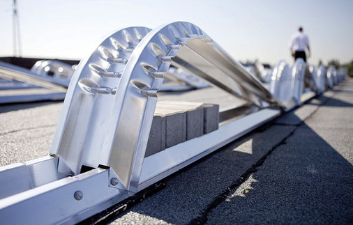 
In der Regel werden die Anlagen mit Betonsteinen ballastiert, damit sie dem Wind widerstehen. Manche Hersteller arbeiten aber auch mit Kiesschüttungen. Der Vorteil ist, dass der Planer präziser an die Grenzen gehen kann. Aber dann besteht die Gefahr, dass die Sicherheitsspanne zu knapp ausfällt.
