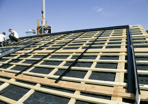 
Für das Indachsystem PV Indax werden zusätzliche Stützbohlen und ein Eindeckrahmen montiert. Bei diesem Montagesystem gewährleisten die Solarmodule auch die Regensicherheit.
