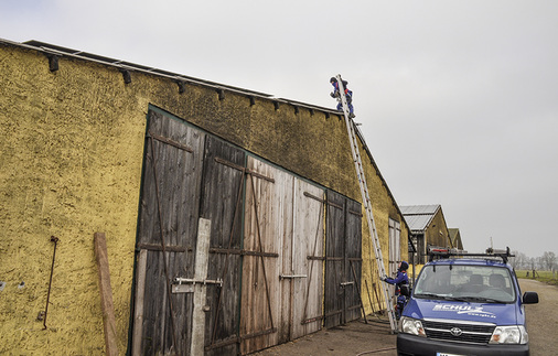 
Das Dach ist nur über den First begehbar. Die beiden Reinigungskräfte besteigen es über eine Leiter.
