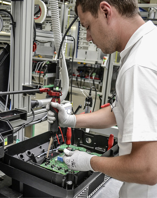 
Produktion in Hagen: Ein Techniker schraubt die Leistungselektronik in das Gehäuse eines Wechselrichters ein. 



