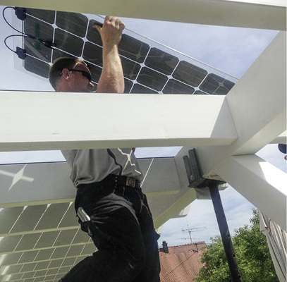 
Montage des Solardaches auf der Terrasse eines Einfamilienhauses: Die rahmenlosen Solarmodule bilden zugleich die Eindeckung des Daches.
