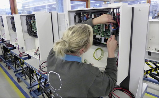 
Manufaktur im Allgäu: Eine Technikerin verkabelt den Wechselrichter im Batterieschrank.
