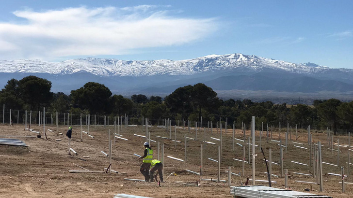 Mit dem Blick auf die hohen Berge der Sierra Nevada bauen die Installateure von Ansasol den Solarpark in Guadix auf unebenem Gelände. - © Schletter
