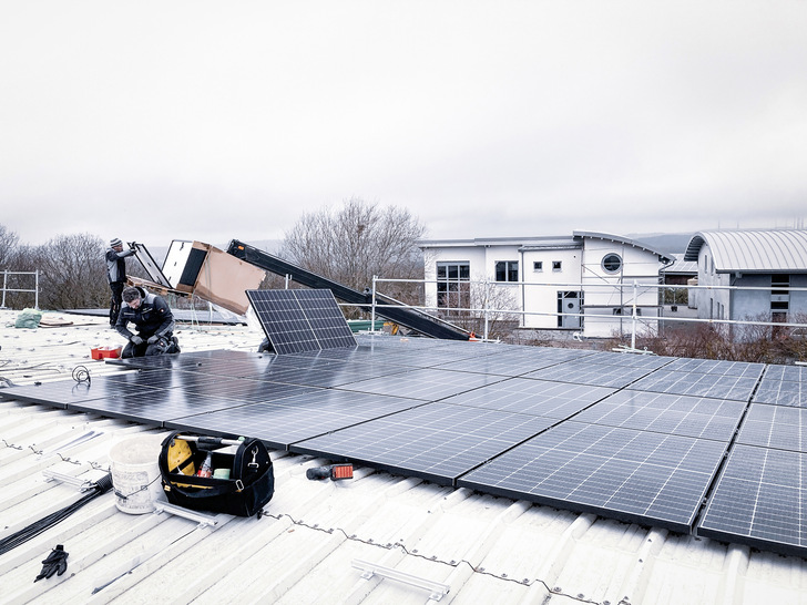 Installateure belegen die Dachfläche mit Modulen. - © Foto: WI Energy
