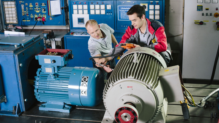 Elektrotechniker und E-Zubi führen Messung an Elektromotor durch.
