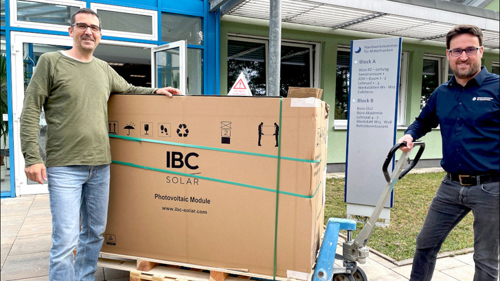 Stefan Seufert, Leiter der DGS Akademie Franken (rechts) und  Michael Dorner, Referatsleiter bei der Handwerkskammer in Nürnberg nehmen das neue Schulungsmaterial von IBC Solar entgegen.