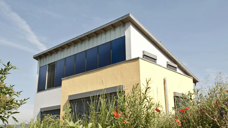  In die Fassade integrierte Flachkollektoren sammeln Sonnenwärme für die Gebäudeversorgung.