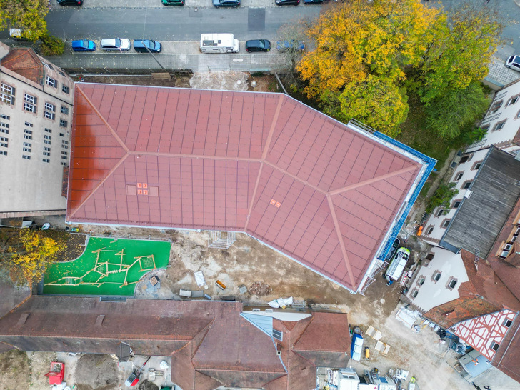 Aus der Vogelperspektive: Auf der gesamten Dachfläche des Schulneubaus in Nürnberg sind rote Indach-Photovoltaikmodule verbaut, um diese farblich einzupassen.