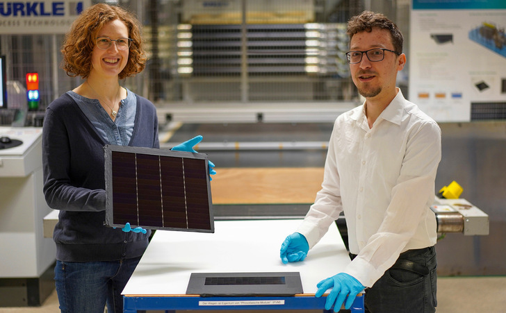 Dr. Laura Stevens vom ISE zeigt das III-V-Germanium-Modul mit 34,2 Prozent Wirkungsgrad. Auf dem Tisch liegt ein III-V-Silizium-Modul mit 31,3 Prozent Effizienz, an dem Leonhard Böck maßgeblich mitgearbeitet hat.