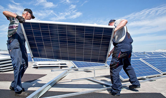 Installateure liefern die Module für ein Flachdach. - © Sunenergy Europe
