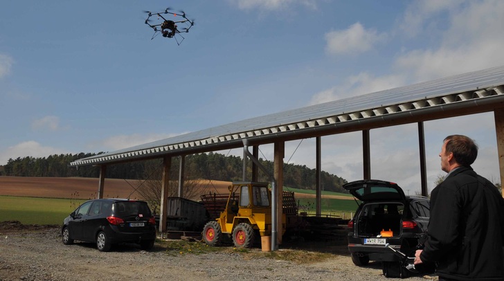 Thomas Reusch überfliegt mit seinem Oktokopter eine Dachanlage. An der Unterseite sind eine Thermografiekamera und eine Echtbildkamera montiert.