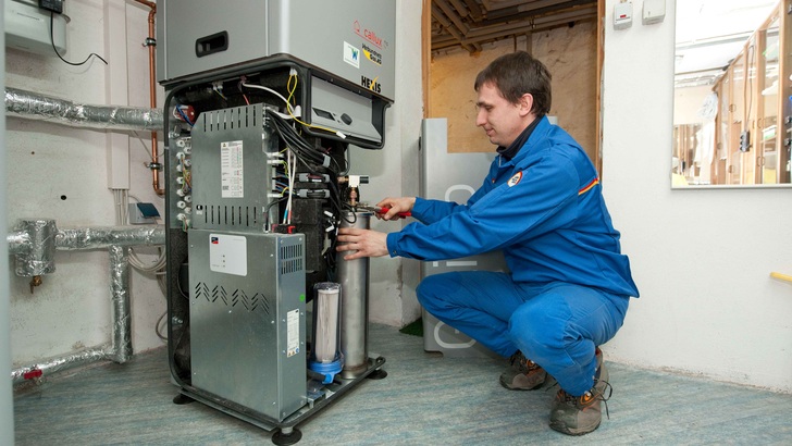 Ein Installateur installiert ein BHKW mit Brennstoffzellen.