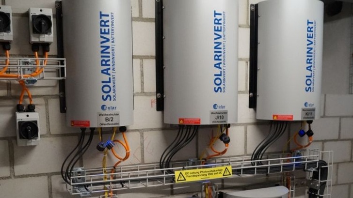 Betriebsraum für Kleinwechselrichter in einem Wohnhaus in Zürich, dessen Fassaden mit Solarmodulen belegt sind.