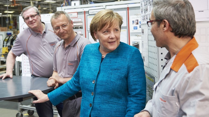 Technik-Fan Merkel im Gespräch mit Viessmann-Mitarbeitern. - © Viessmann
 Technik-Fan Merkel im Gespräch mit Viessmann-Mitarbeitern.