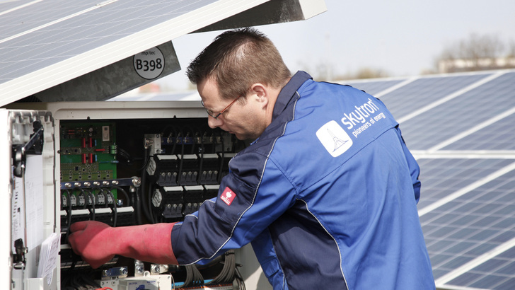 Dieser Handwerker macht es richtig. Er trägt isolierende Elektrikerhandschuhe, wenn er in den Anschlusskasten greift, um Wartungsarbeiten durchzuführen. Sie sind für Arbeiten in Spannungsbereichen bis 1.000 Volt konzipiert. - © Skytron
