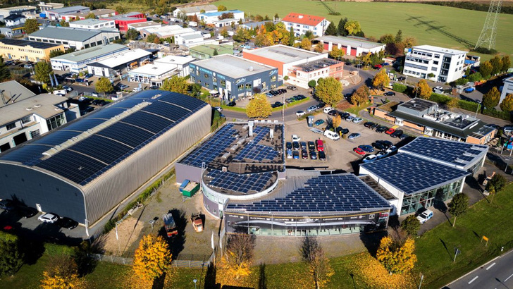 Alles auf Photovotlaik umgestellt: Das Tonnendach (links) ist mit Dünnschichtmodulen belegt. Dazwischen schimmern einige kristalline Paneele durch. Jetzt wurde auch das Autohaus (rechts) mit einer Solaranlage ausgestattet. - © P. Antonius Rösing
