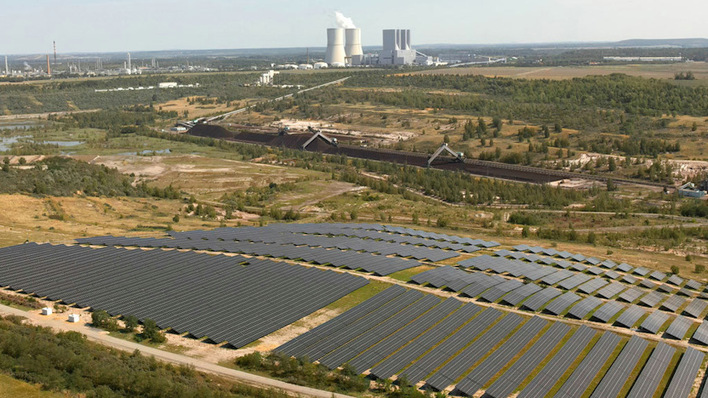 Blick über den neuen Solarparks zum Heizkraftwerk, das noch aus der Kohleära stammt.