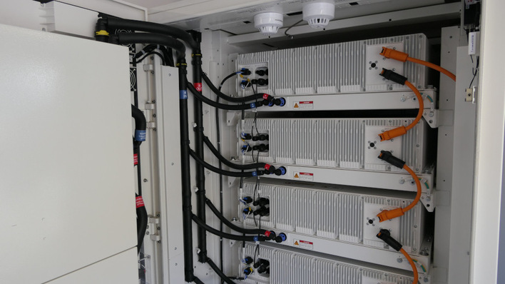 Server-Rack mit mehreren miteinander verbundenen weißen Geräten, orangefarbenen Kabeln und schwarzen Schläuchen. - © Niels H. Petersen
