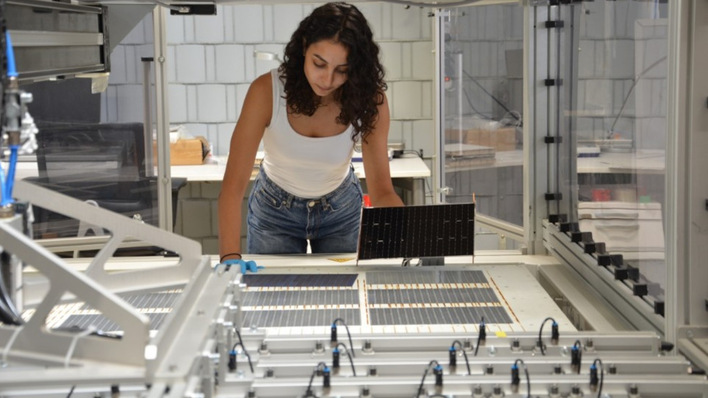 Die Projektleiterin am Fraunhofer ISE, Najwa Abdel Latif kontrolliert die verschalteten Solarzellen am Schindel-Matrix-Stringer des Fraunhofer ISE.