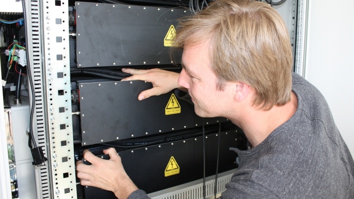 Hier kontrolliert ein Handwerker die Anschlüsse in einem Batterieconatiner eines Gewerbespeichers.